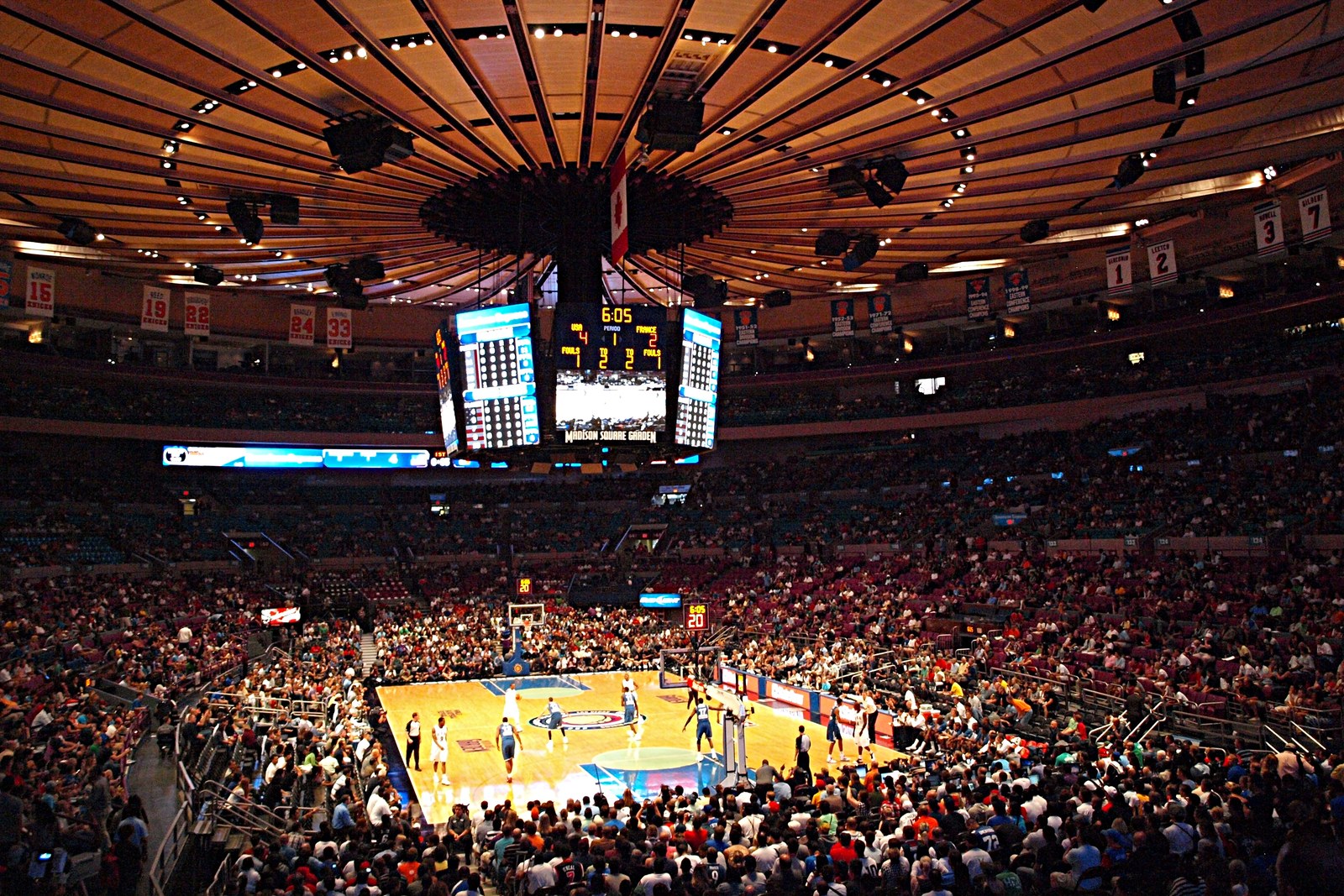 Sold-out basketball game at Madison Square Garden in New York: full crowd, jumbotron and court action under the iconic ceiling.